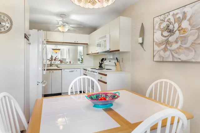 a very nice looking kitchen with granite countertop a stove a sink and a chandelier
