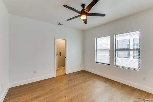 an empty room with wooden floor and windows