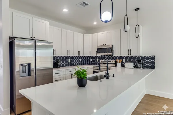 a kitchen with stainless steel appliances granite countertop a refrigerator a sink a stove and white cabinets