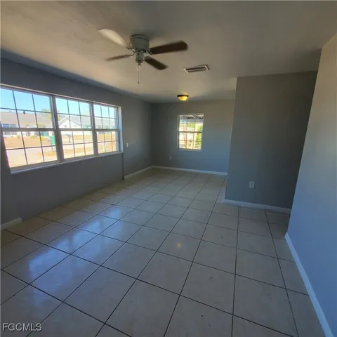 an empty room with windows and fan
