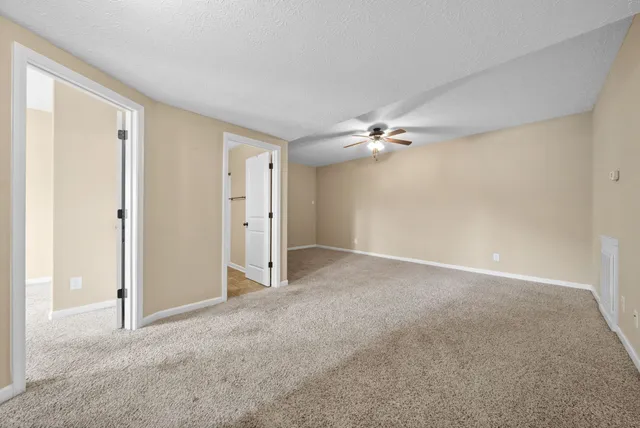 a view of an empty room with a chandelier fan