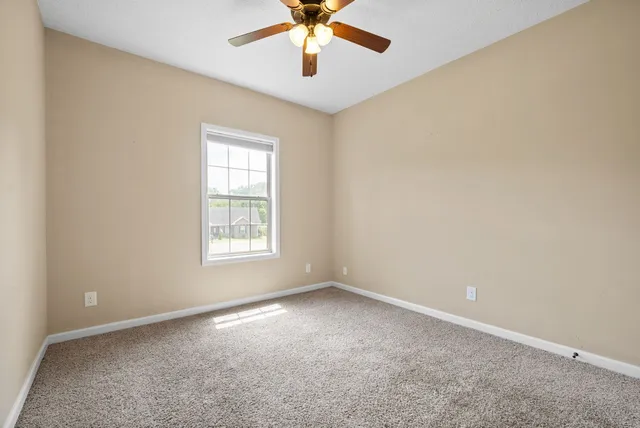 an empty room with a ceiling fan and a window