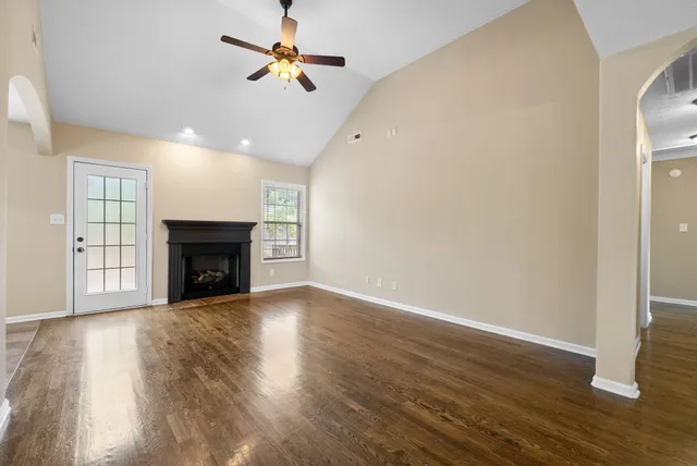 a view of an empty room with wooden floor fireplace and a window