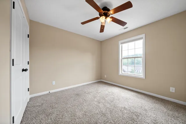 an empty room with windows and fan