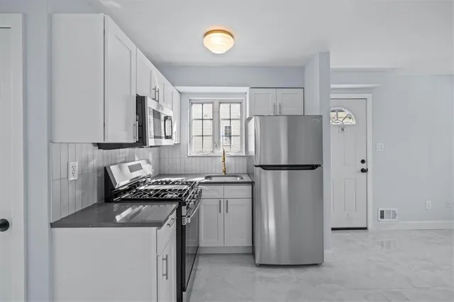 a kitchen with stainless steel appliances granite countertop a refrigerator a stove a sink and a microwave