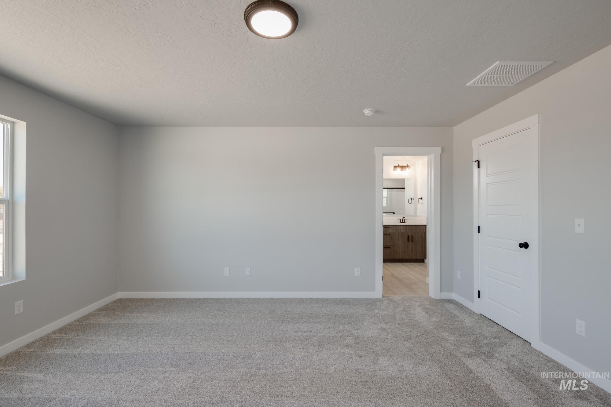 2058 South Border Way Meridian, ID 83642 - Photo 15 of 25 Unfurnished bedroom with light carpet, ensuite bath, and a textured ceiling