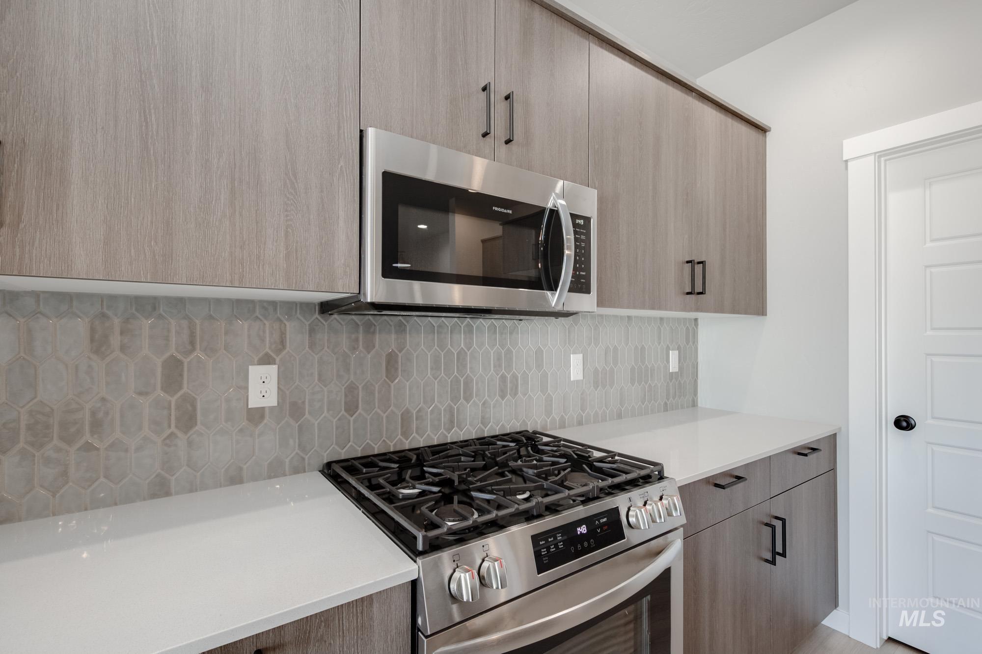 2058 South Border Way Meridian, ID 83642 - Photo 6 of 25 Kitchen featuring stainless steel appliances, modern cabinets, decorative backsplash, and light stone counters
