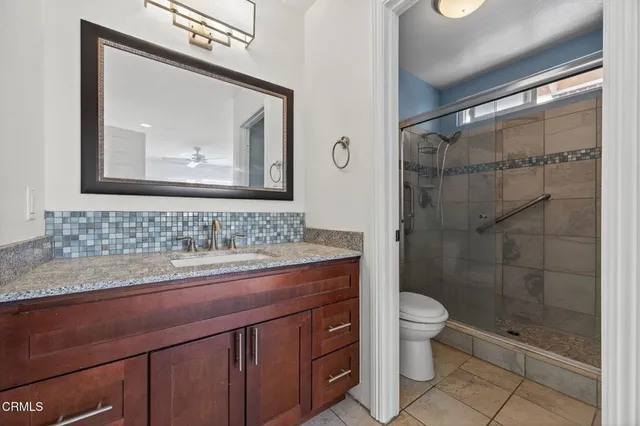 a bathroom with a granite countertop sink a toilet a mirror and shower