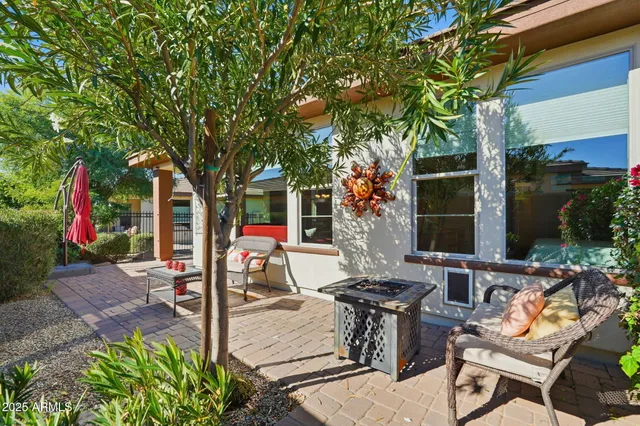 a view of a patio with table and chairs potted plants and large tree