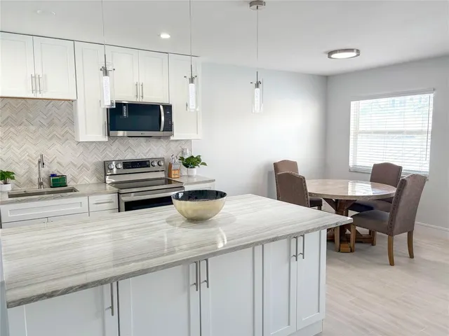 a kitchen with stainless steel appliances a white table chairs and a refrigerator