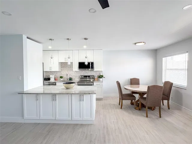 a kitchen with stainless steel appliances a stove a sink a refrigerator and white cabinets