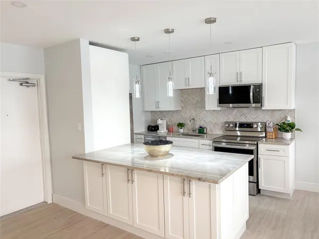 a kitchen with stainless steel appliances a stove a microwave a sink and cabinets
