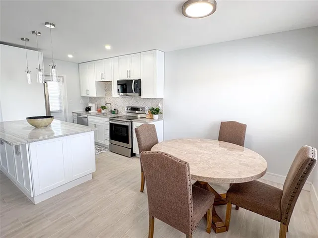 a kitchen with stainless steel appliances granite countertop a stove top oven a sink a refrigerator white cabinets and wooden floor