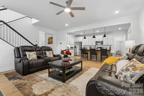 a living room with furniture kitchen view and a chandelier