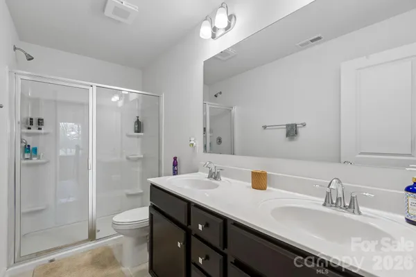 a bathroom with a granite countertop sink a toilet a shower and a mirror