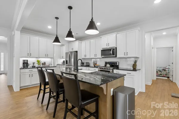 a kitchen with stainless steel appliances granite countertop a stove top oven a refrigerator a sink and chairs