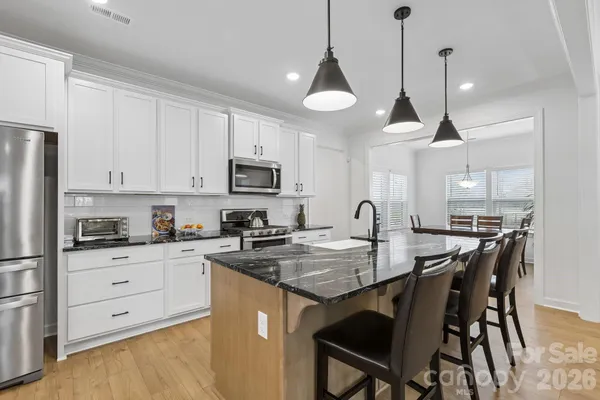 a kitchen with stainless steel appliances granite countertop a kitchen island a stove a table and chairs