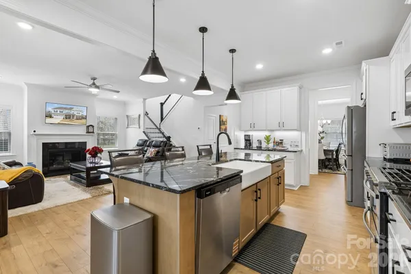 a kitchen with stainless steel appliances granite countertop a sink a stove and a wooden floor