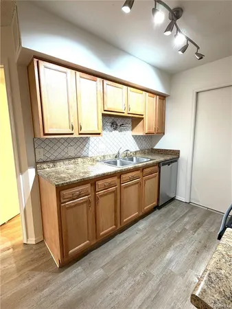 a kitchen with granite countertop a sink cabinets and wooden floor