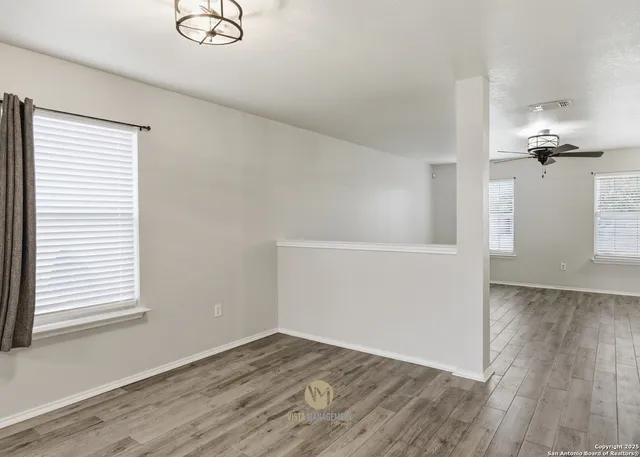 an empty room with wooden floor cabinet and windows