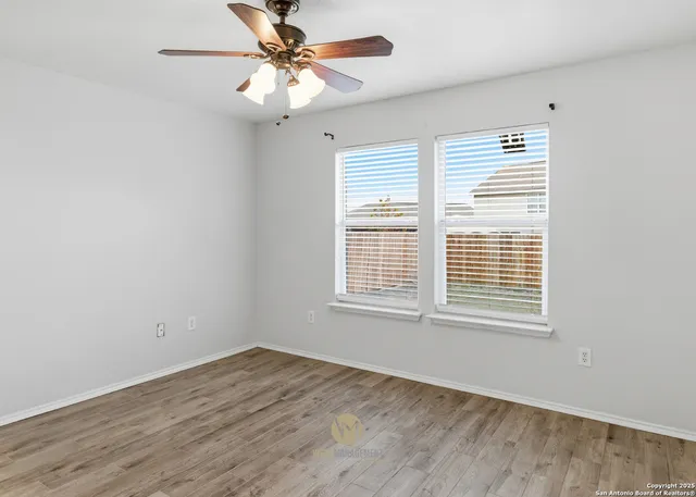 a view of an empty room with a window and a chandelier fan