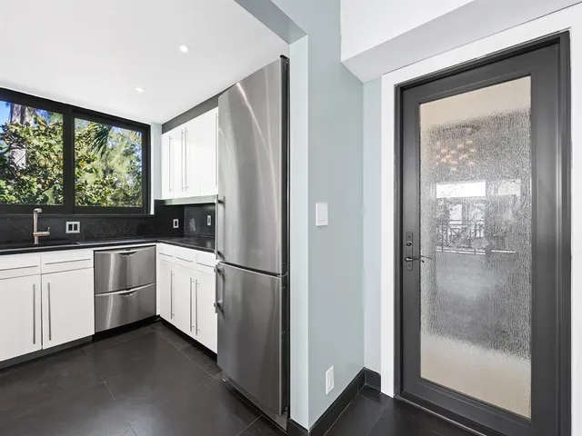 a kitchen with a refrigerator and white cabinets
