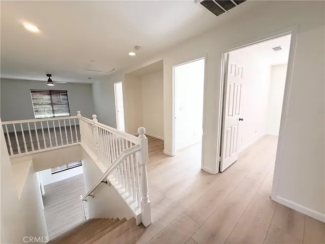 a view of a hallway with wooden floor and windows