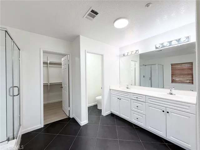 a spacious bathroom with a double vanity sink a mirror and a shower