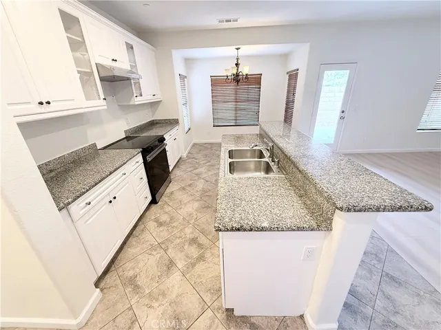 a kitchen with granite countertop a sink stove and cabinets