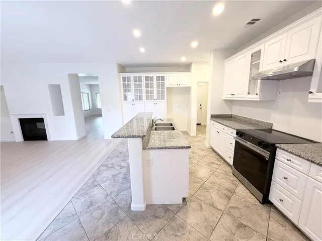 a large kitchen with stainless steel appliances kitchen island granite countertop a sink and cabinets