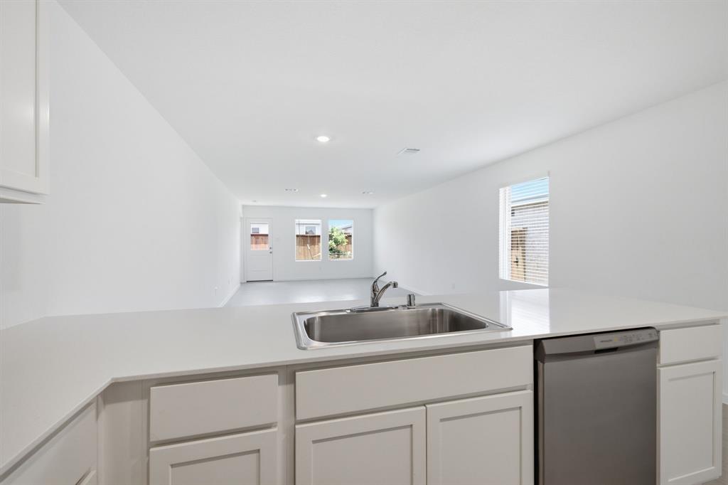 2128 Doc Holliday Road Joshua, TX 76058 - Photo 15 of 28 Kitchen island featuring a stainless steel sink, contemporary faucet, and integrated dishwasher