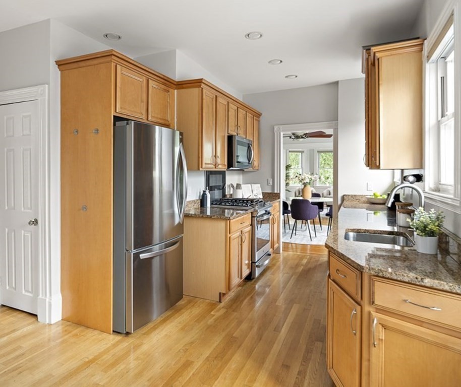 50 Beacon Street, Unit 3 Somerville, MA 02143 - Photo 7 of 15 a kitchen with stainless steel appliances granite countertop a refrigerator a stove a sink dishwasher and a dining table with wooden floor