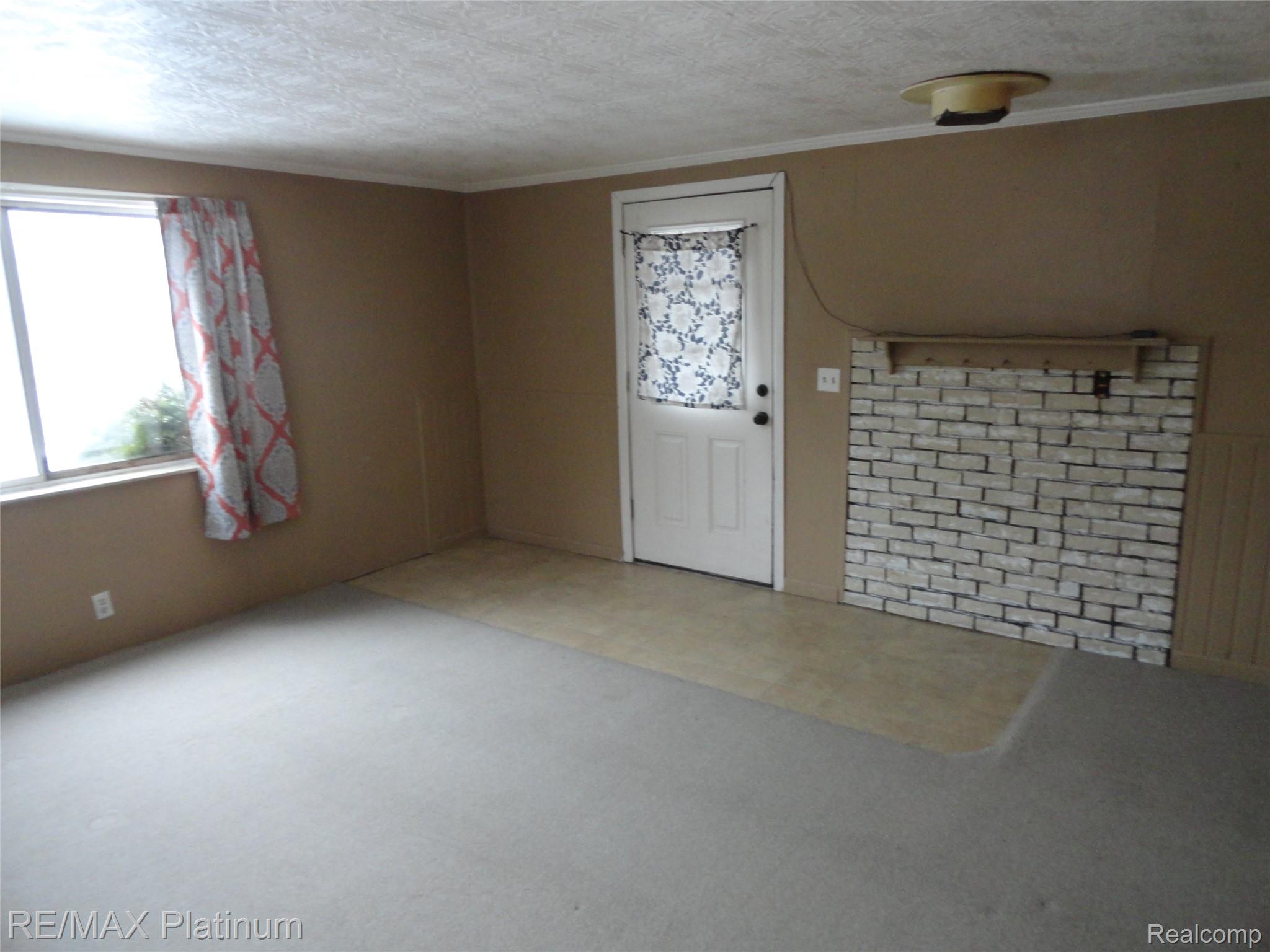 3396 East Baldwin Road Grand Blanc, MI 48439 - Photo 10 of 16 Entryway featuring a textured ceiling, ornamental molding, and carpet