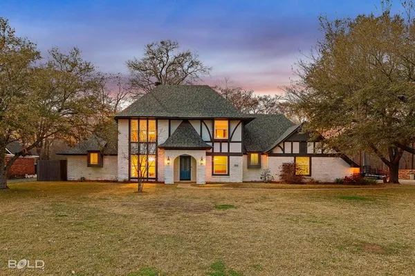 a large tree in front of house with a yard