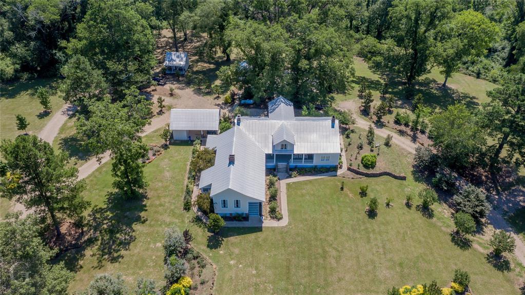 an aerial view of a house with a yard swimming pool and large trees