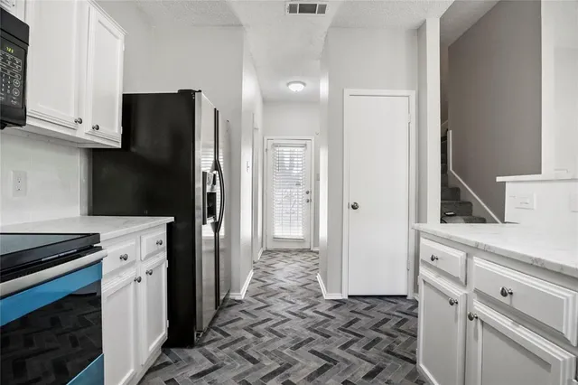 a kitchen with a refrigerator stove and white cabinets