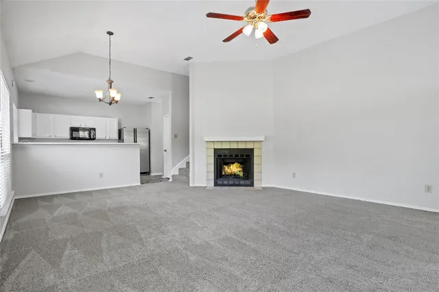 a view of a kitchen with a fireplace a ceiling fan and windows