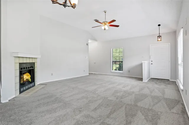 a view of an empty room with window and kitchen view