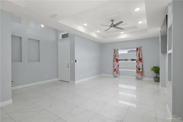 an empty room with windows and ceiling fan