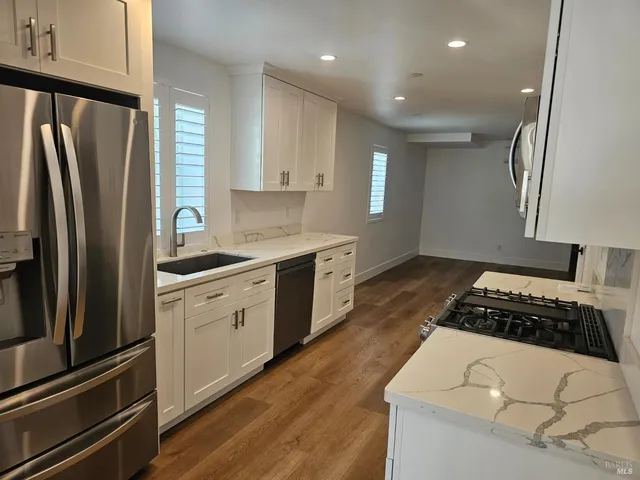 a kitchen with granite countertop a refrigerator stove and sink