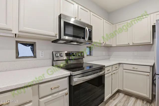 a kitchen with white cabinets and refrigerator