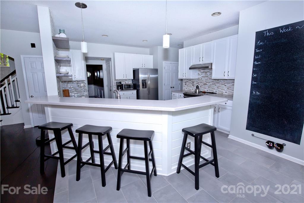 20200 Tailwind Lane Cornelius, NC 28031 - Photo 11 of 28 a kitchen with stainless steel appliances kitchen island granite countertop a table chairs sink and cabinets