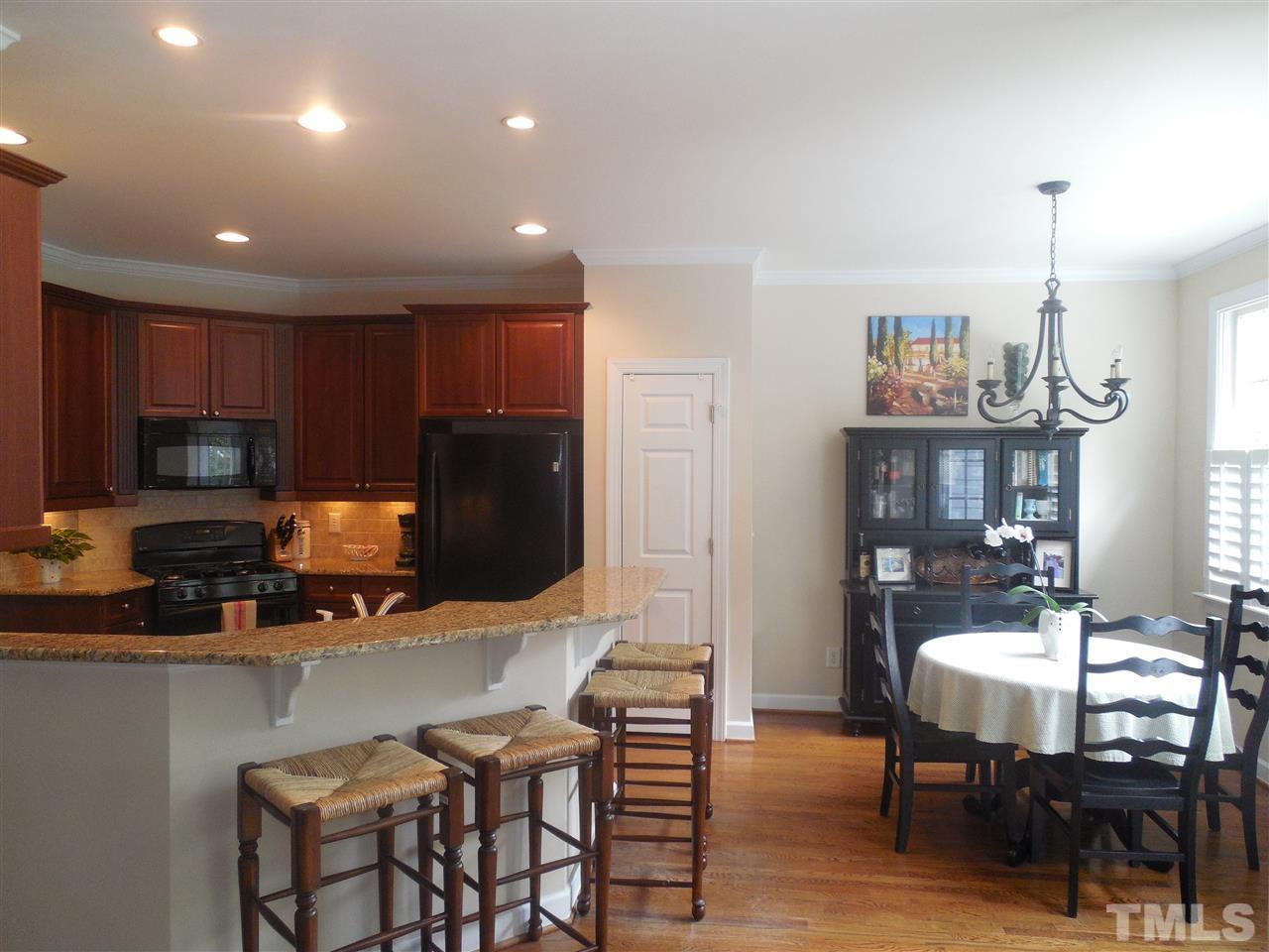 1618 Weatherford Circle Raleigh, NC 27604 - Photo 8 of 20 a kitchen with stainless steel appliances granite countertop a stove top oven a sink a refrigerator with a dining table and chairs with wooden floor