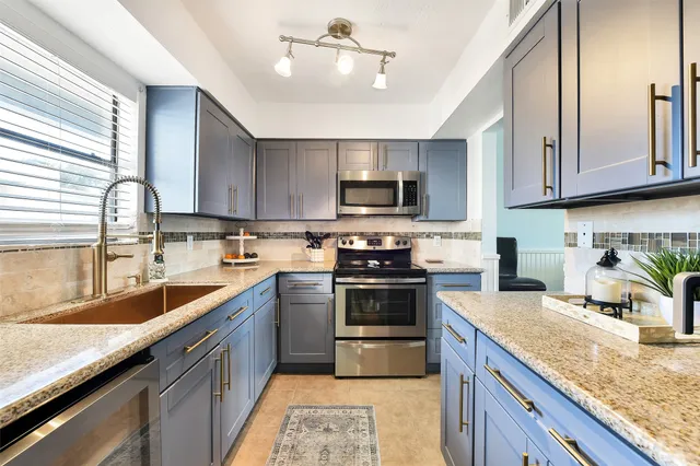a kitchen with stainless steel appliances granite countertop a sink stove microwave and refrigerator