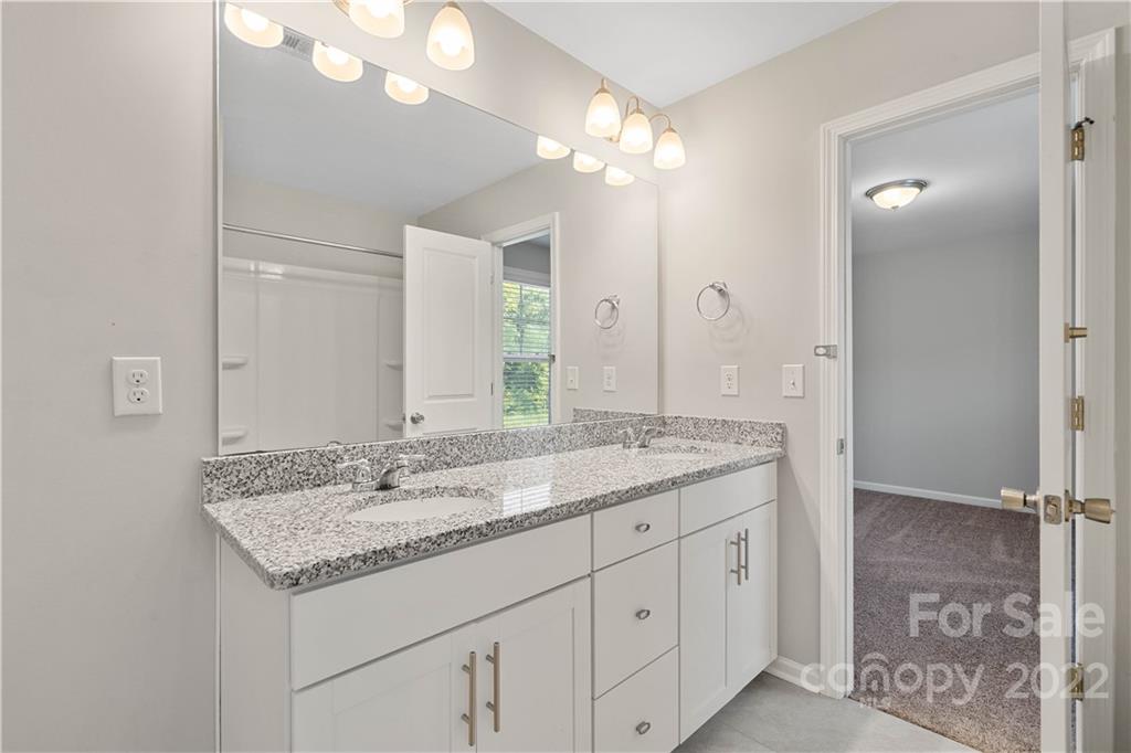 4025 Shadowbrook Road Waxhaw, NC 28173 - Photo 28 of 48 a bathroom with a granite countertop sink a large mirror and a shower
