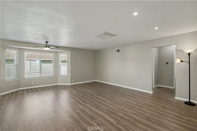 an empty room with wooden floor and windows