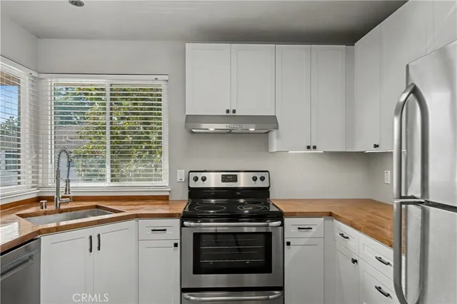 a kitchen with granite countertop a sink stainless steel appliances and window
