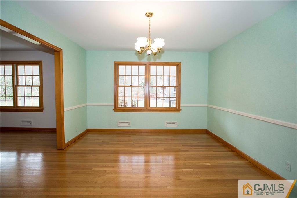 103 Buchanan Road Edison, NJ 08820 - Photo 7 of 25 an empty room with wooden floor chandelier and windows