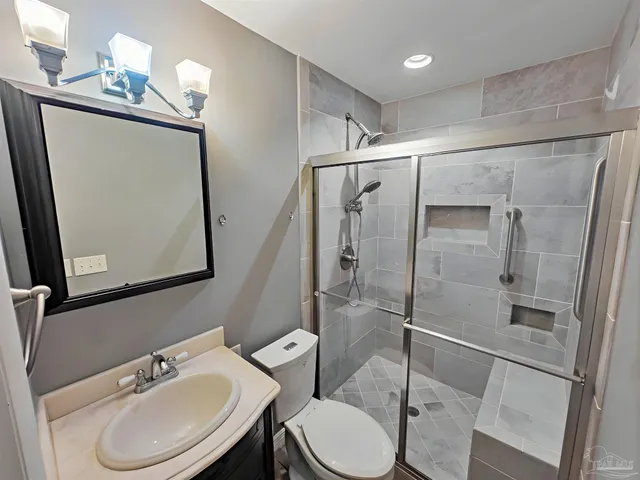 a bathroom with a sink a toilet a mirror and shower