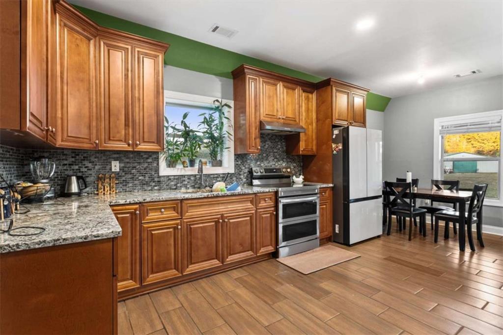 1740 Gratis Road Monroe, GA 30656 - Photo 11 of 26 a kitchen with stainless steel appliances granite countertop wooden floor a stove a sink dishwasher and a refrigerator with wooden floor